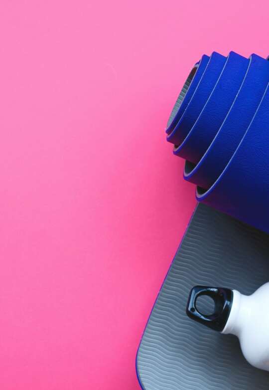 Bright blue yoga mat on a pink background