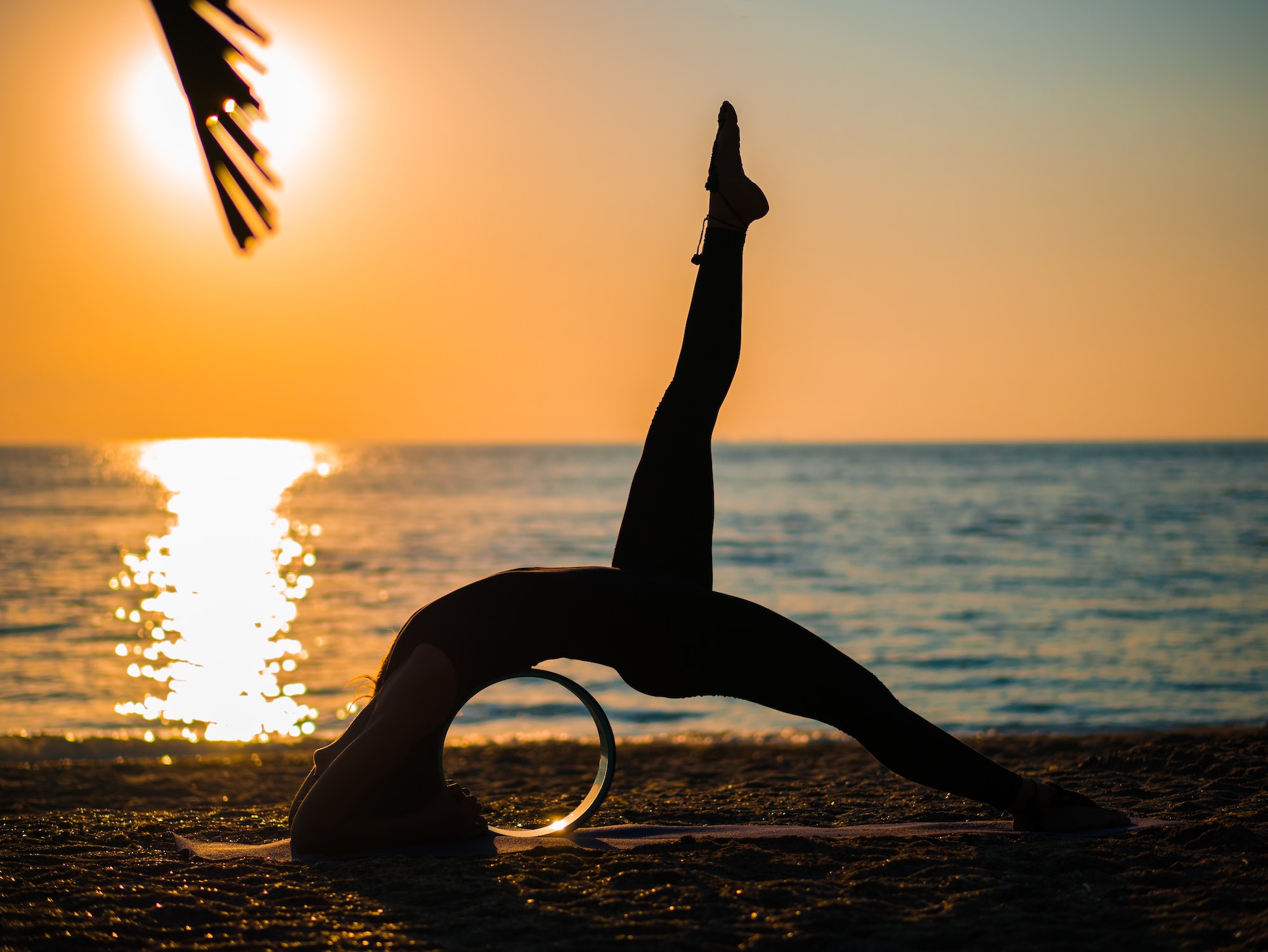 Silhouette of woman doing yoga with yoga wheel